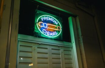 Glowing neon sign reading Premium Cigars with cigar illustration, mounted in a window at night in Raleigh NC smoke shop